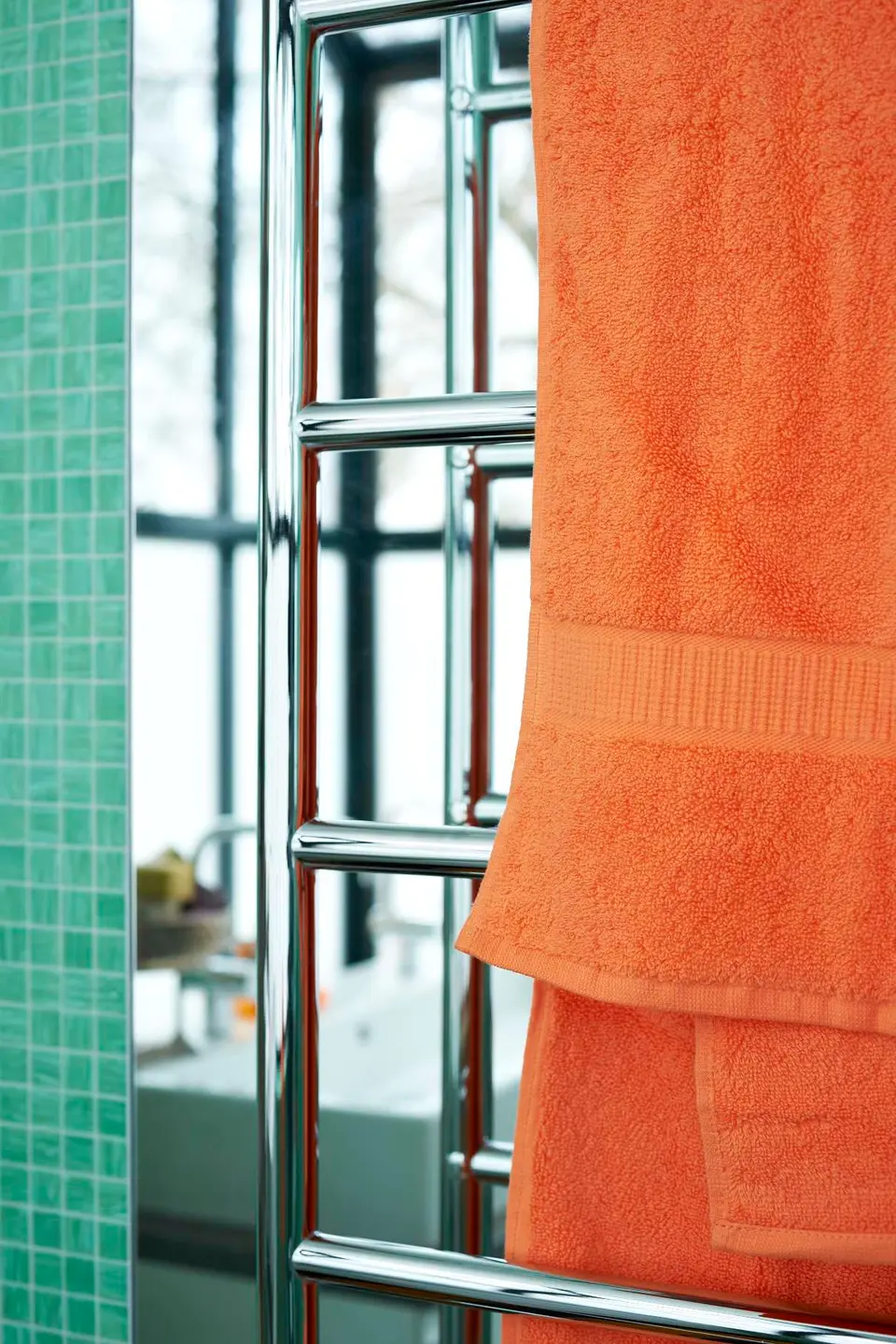 Orange handdukar på handdukstork mot grön mosaik, villa i Djursholm