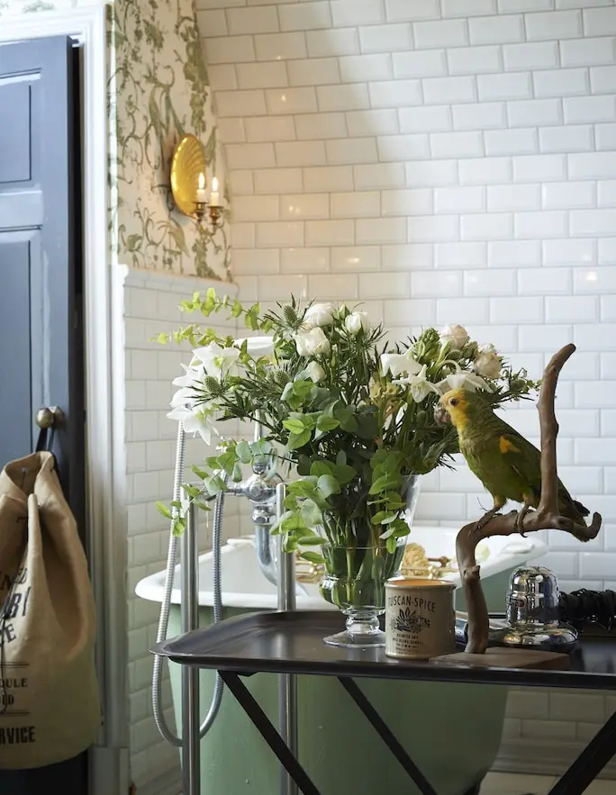 Bord med blommor och en uppstoppad papegoja vid badkaret, skärgårdshus på Yxlan