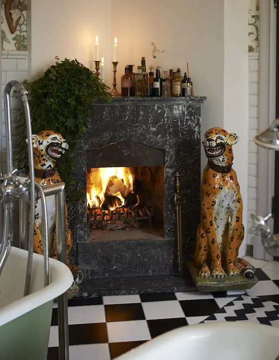 Öppen spis i marmor i badrummet, flankerad av två leopardfigurer, skärgårdshus på Yxlan