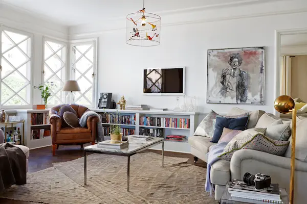 Ljust vardagsrum med spröjsade fönster, konst och fåtöljer, våningen Dusty Deco