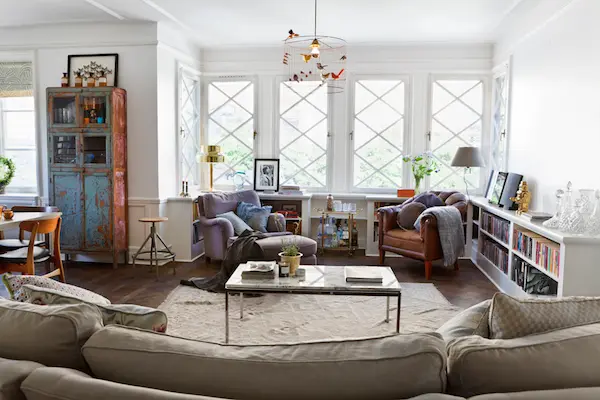 Vardagsrum med turkost vitrinskåp och stor soffa, våningen Dusty Deco