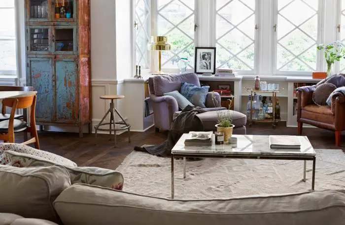 Vardagsrum med spröjsade fönster, turkost vitrinskåp och skinnfåtölj, våningen Dusty Deco