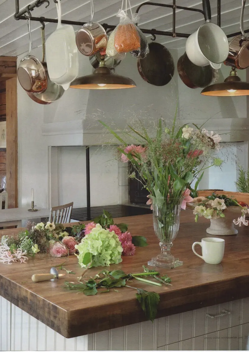 Köksö i trä med blommor under kopparkastruller, gården Segersta