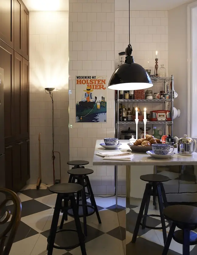 Kök med pendellampa, barstolar och schackrutigt golv, våning på Östermalm