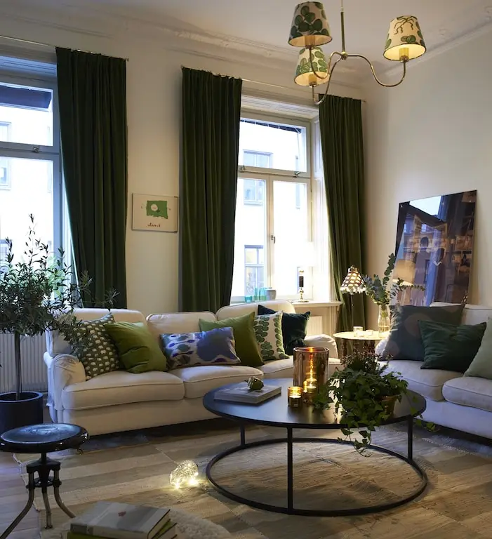 Vardagsrum med gröna sammetsgardiner, ljus soffa och runt soffbord, våning på Östermalm