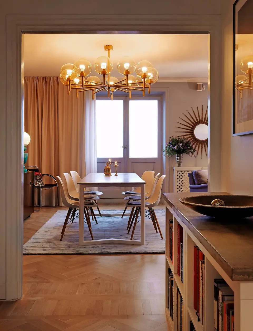 Matplats med mässingskrona och vita stolar, sedd genom en dörröppning, Alexandra Pascalidous hem i Stockholm