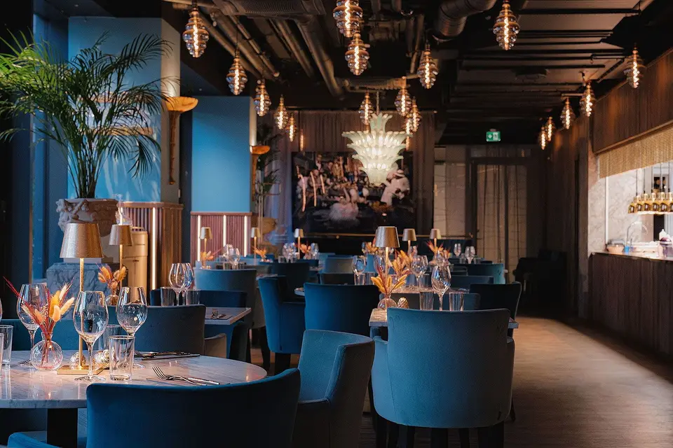 Matsal med palmer, blå sammetsstolar och kristallkronor, Restaurang Pava, Stockholm