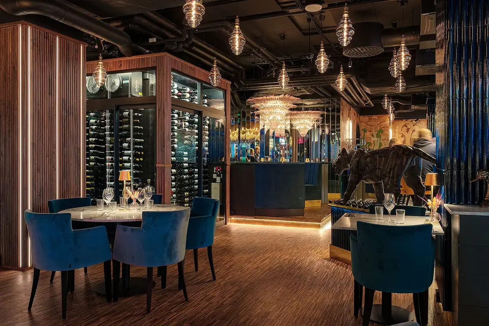 Matsal med vinkyl i glas, rörformad panel och blå stolar, Restaurang Pava, Stockholm