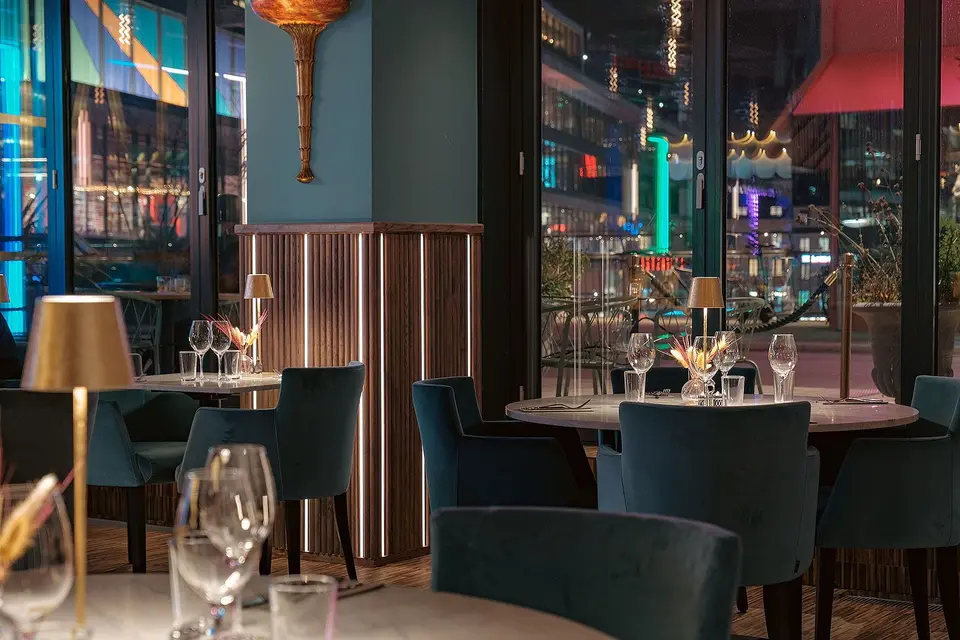 Matsal vid fönstren med mässingslampor på borden, Restaurang Pava, Stockholm