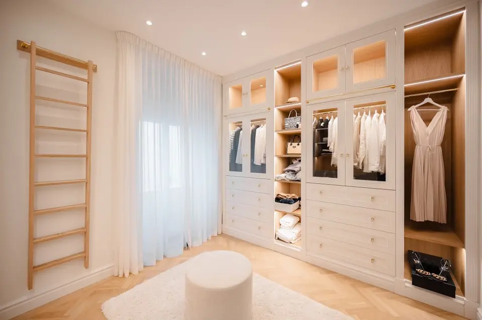 Walk-in closet med glasade skåp, lådor och stege på skena, våning på Strandvägen, Östermalm